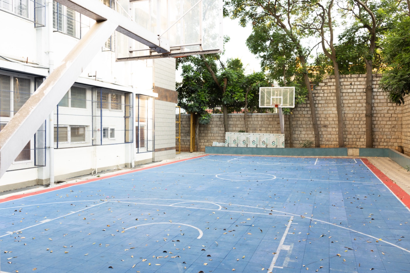 Outdoor basketball court on campus with hoop and marked playing area